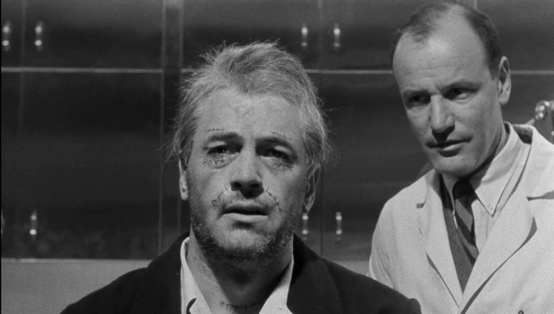 In this image from Seconds, Arthur Hamilton is now played by Rock Hudson, staring at the camera with surgical scars alongside the surgeon (Richard Anderson)
