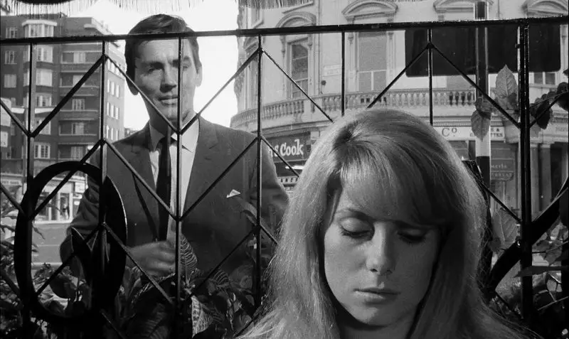 In this image from Repulsion, the character Colin (John Fraser) is depicted behind a gate, addressing Carol, who is seated in a restaurant.