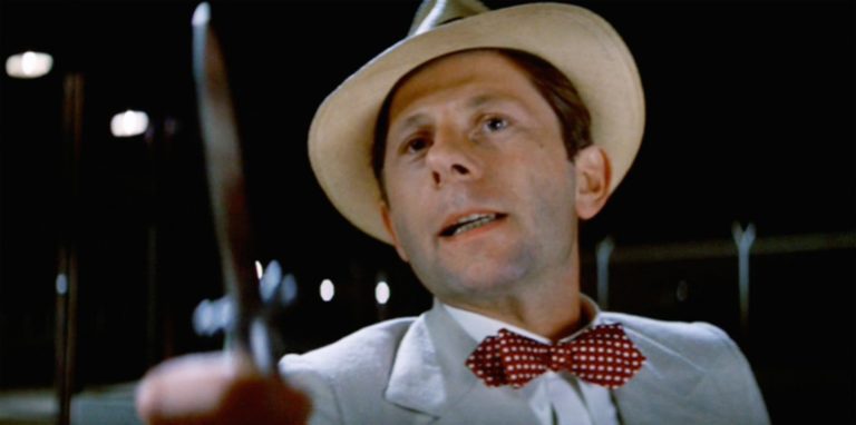 In this image from Chinatown, Roman Polanski is depicted in a straw hat, seersucker jacket, and bowtie holding a knife.