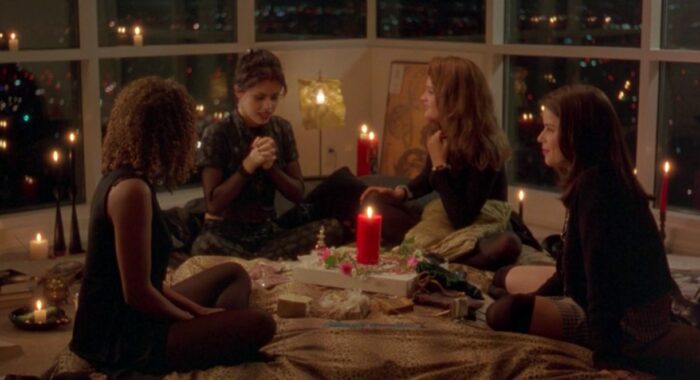 The teen girls sit in a circle to stereotypically play with magic in Nancy's new LA high rise in The Craft.