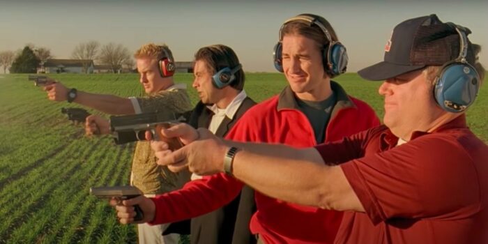 Four men, including Luke and Owen Wilson, shoot guns in a field.