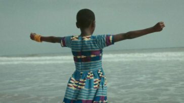 Still from Da Yie. A young girl stands triumphantly in front of the ocean.