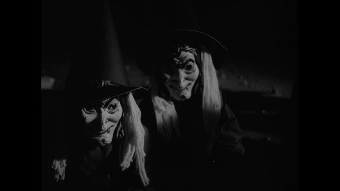 Still from A Scary Time, a short film added to Criterion Channel in September. Two children in witch masks look at the camera. Black and white shot.