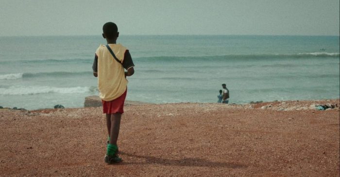 Still from Da Yie, one of the short films added to Criterion Channel in September. A young boy walks towards a beach with a man and a young girl in the distance.