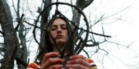 A teen girl forms a symbol out of sticks.