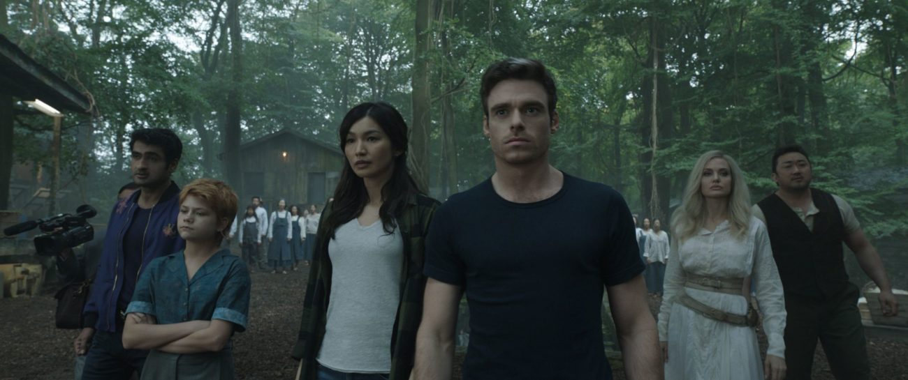 The Eternals assemble to watch a threatening creature in a forest.