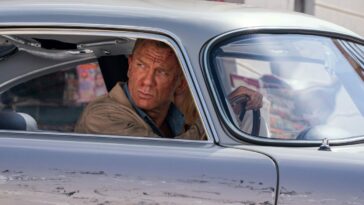 James Bond looks out his damaged car towards his pursuers.