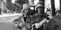 Two women in hats meet on the street.