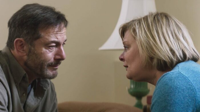 Jay (Jason Isaacs) comforts his grieving wife Gail (Martha Plimpton)