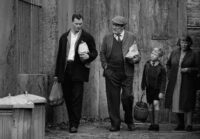 Three generations of men walk back from a market.