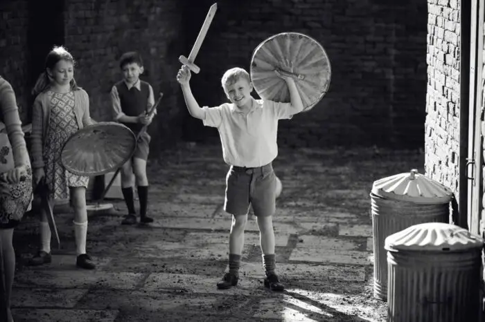 A boy with a makeshift sword and shield plays with his friends.