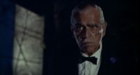 An older man with a white mustache wearing a black suit and bowtie stands in the darkness with a serious expression on his face (Boris Karloff in Peter Bogdanovich's film Targets)