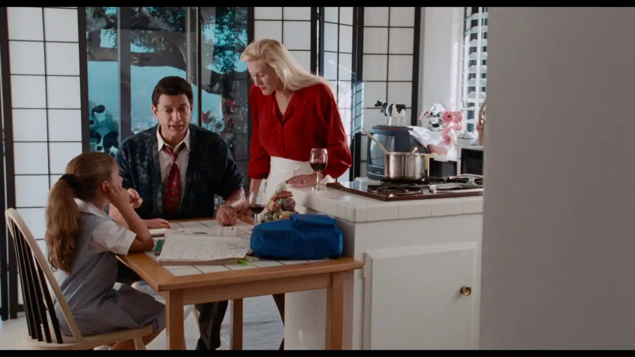 Image from Deep Cover: David Jason (Goldblum) is depicted in an all-white contemporary kitchen with his blond wife and young child.