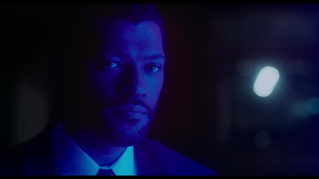 Image from Deep Cover: Stevens/Hull (Fishburne) is depicted in close-up, lit with a brilliant blue neon light.