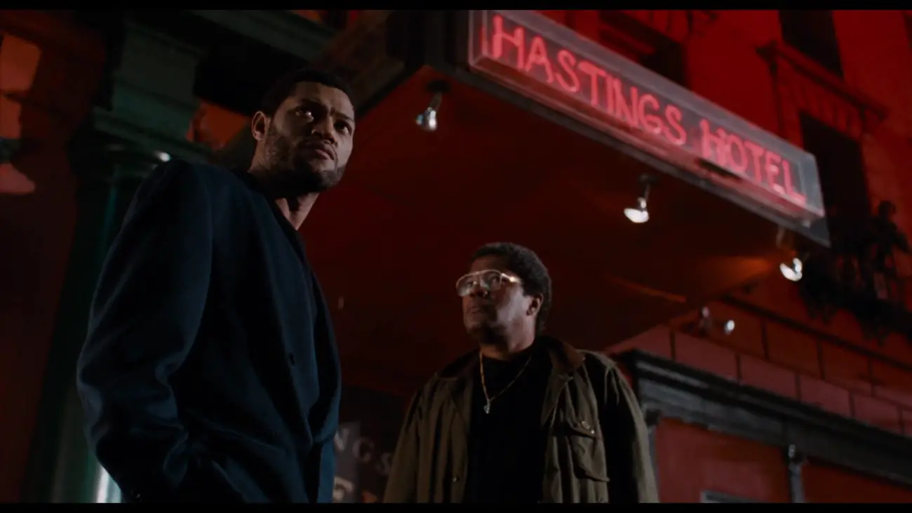 Image from Deep Cover: John Stevens (Laurence Fishburne) and Officer/Reverend Taft (Clarence Williams III) stand in front of a red neon sign "Hastings Hotel."