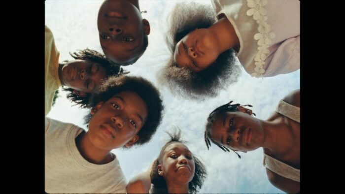 Screenshot from Don't Go Tellin' Your Momma. A group of children stare downwards, as if looking at someone lying on the ground.