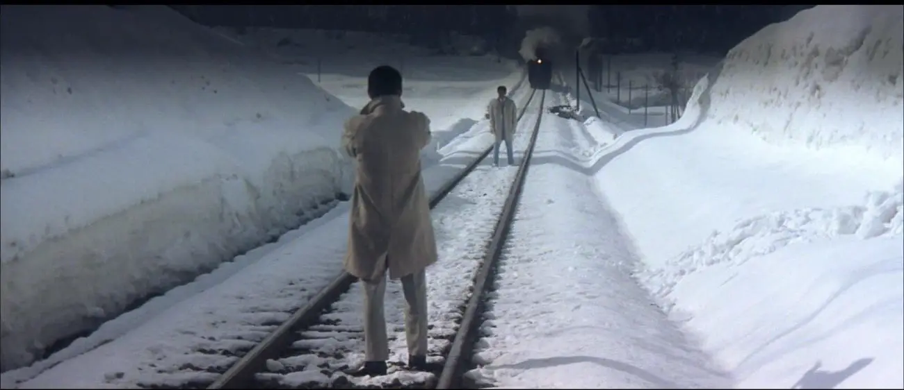 Image from Tokyo Drifter: Tetsu stands on railroad tracks between rival Tatsu and an oncoming locomotive.