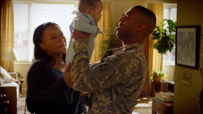 A soldier holds up his baby next to his mother
