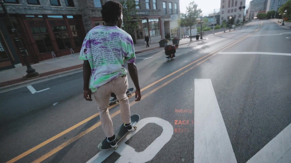 Image from Minding the Gap: A young black man (Keire Johnson) skateboards down a city street.