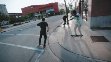 Young men skateboarding through city streets