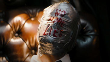 A person's face wrapped in duct tape with "No More Lies" scrawled in red from The Batman trailer