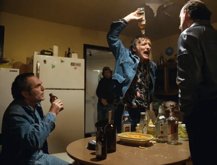 Dennis Hopper as Don, pouring a bottle of liquor over his head.