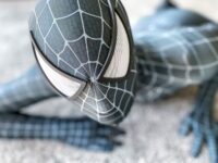 A black-suited Spider-Man crawls on a wall in close-up.