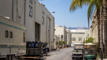 A service road down a studio lot shows the Hollywood sign in the distance.
