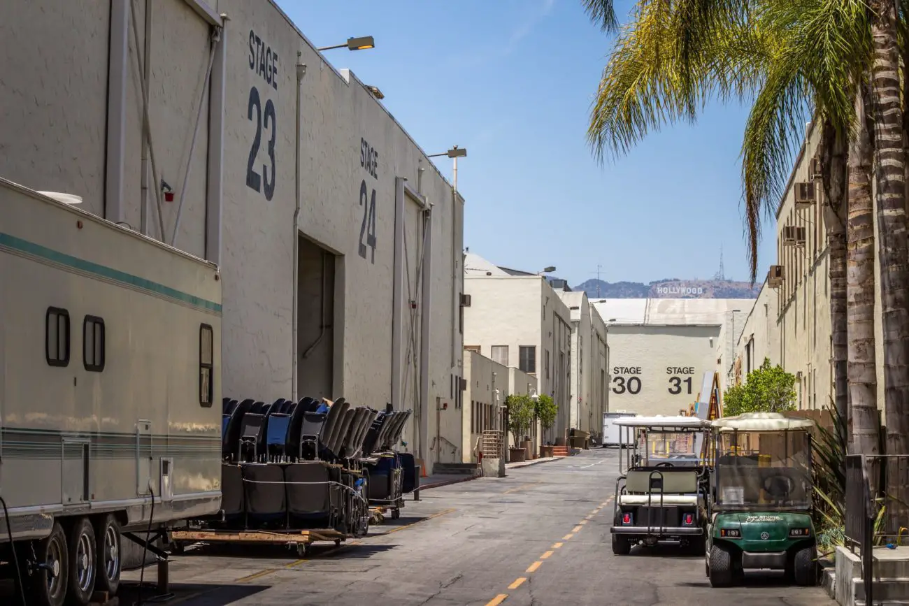 A service road down a studio lot shows the Hollywood sign in the distance.