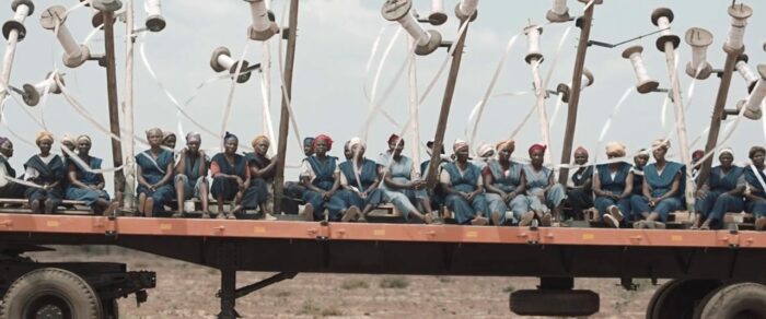 Old African women sitting on a platform truck with white ribbons floating in the air