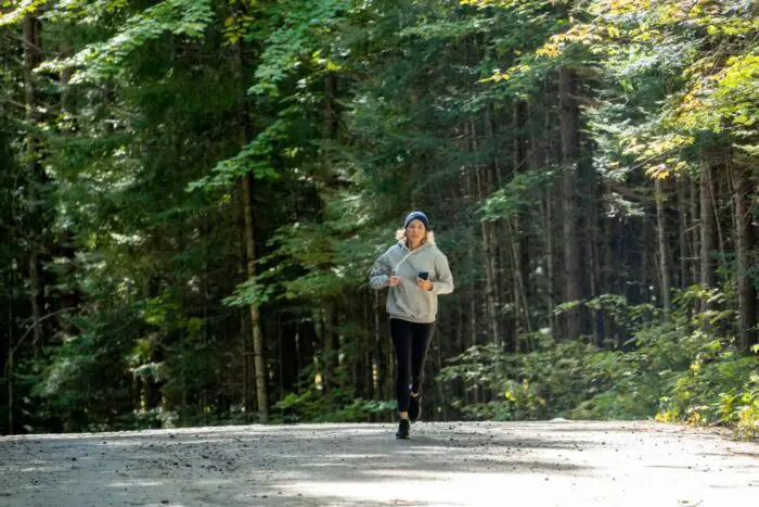 A woman is jogging in the woods.