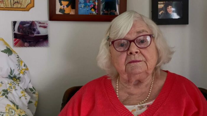 An elderly woman records a video.