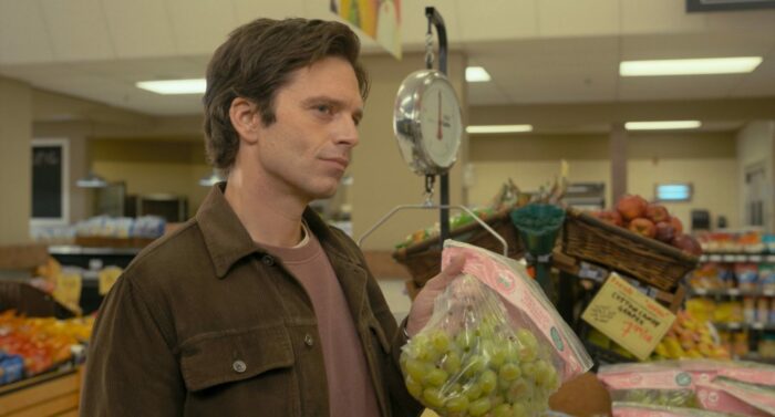 A man offers grapes to a woman at a supermarket.