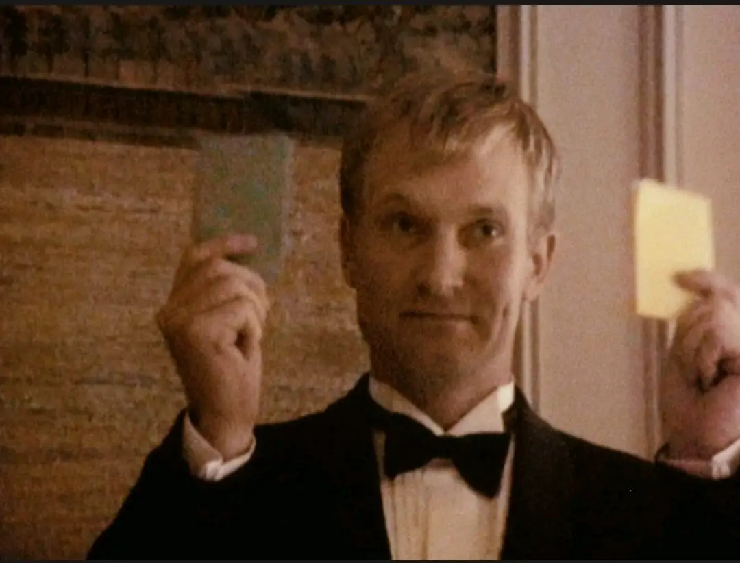 Image from The Celebration: A medium shot of Christian (Ulrich Thomsen) holding a green paper in one hand, and a yellow paper in the other hand.