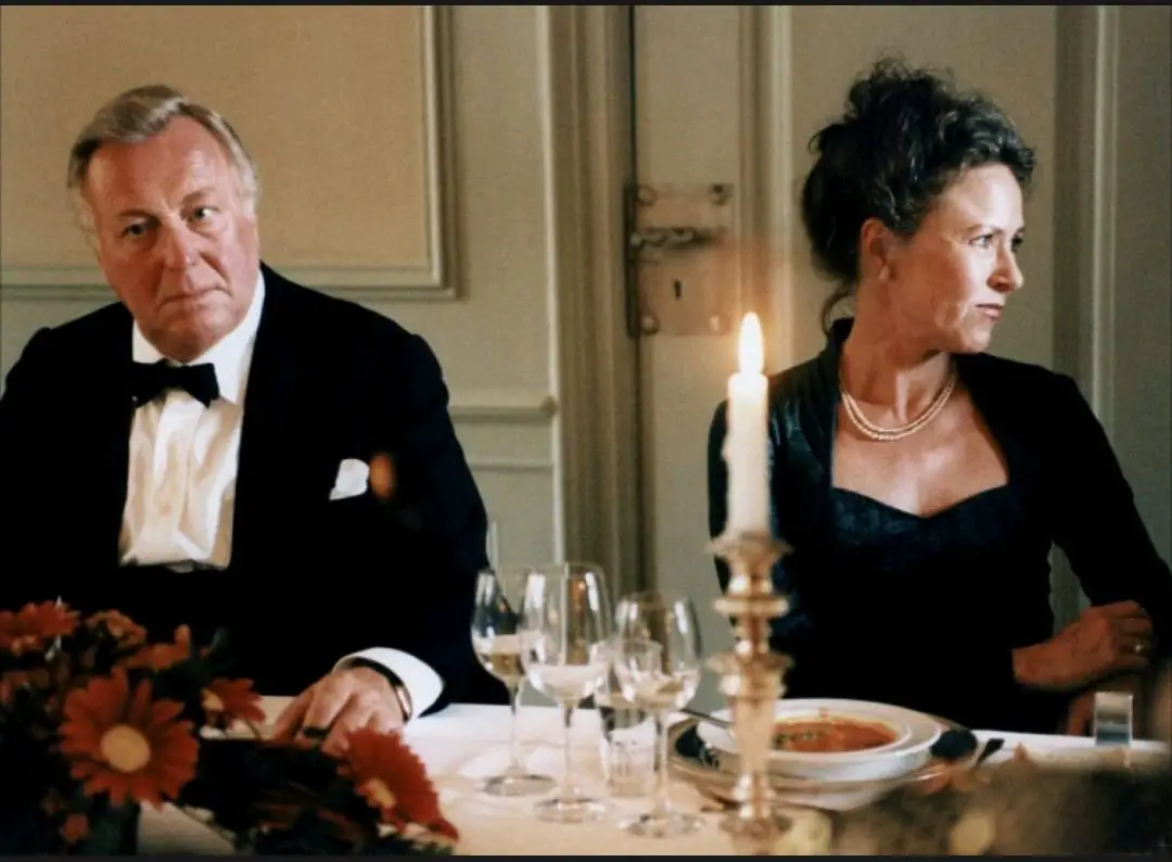 Image from The Celebration: A medium shot of Helge (Henning Moritzen) and his wife Else (Birthe Neumann) sitting by each other at a dinner table.