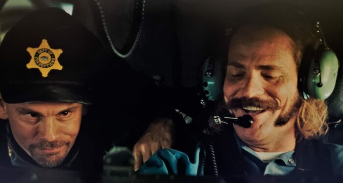 M. C. Gainey as Swamp Thing takes the controls of the plane in Con Air with John Malkovich beside him disguised as a guard