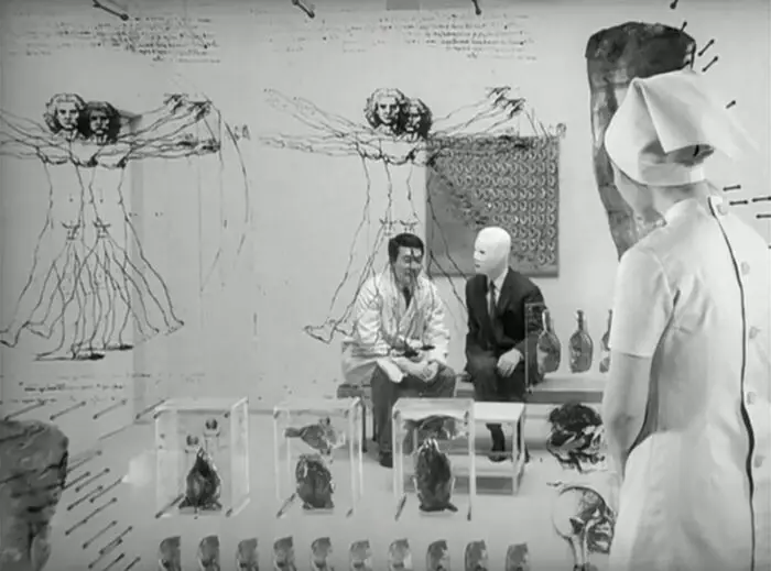 Image from The Face of Another: A doctor and a faceless man sit in an office decorated with images of da Vinci's Vitruvian Man as a nurse in the foreground observes them.