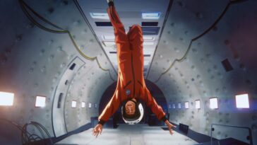 A young boy floats upside down in zero gravity on a jetplane.