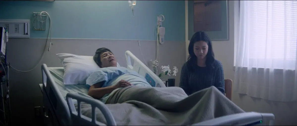 Image from In A New York Minute: Amy (Amy Cheng) sits with her mother (Cheng Pei Pei) in a hospital.