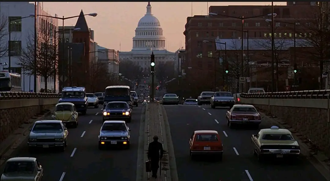 A long shot of Chance (Peter Sellers) walking down a busy Washington D.C. road in the divider section.