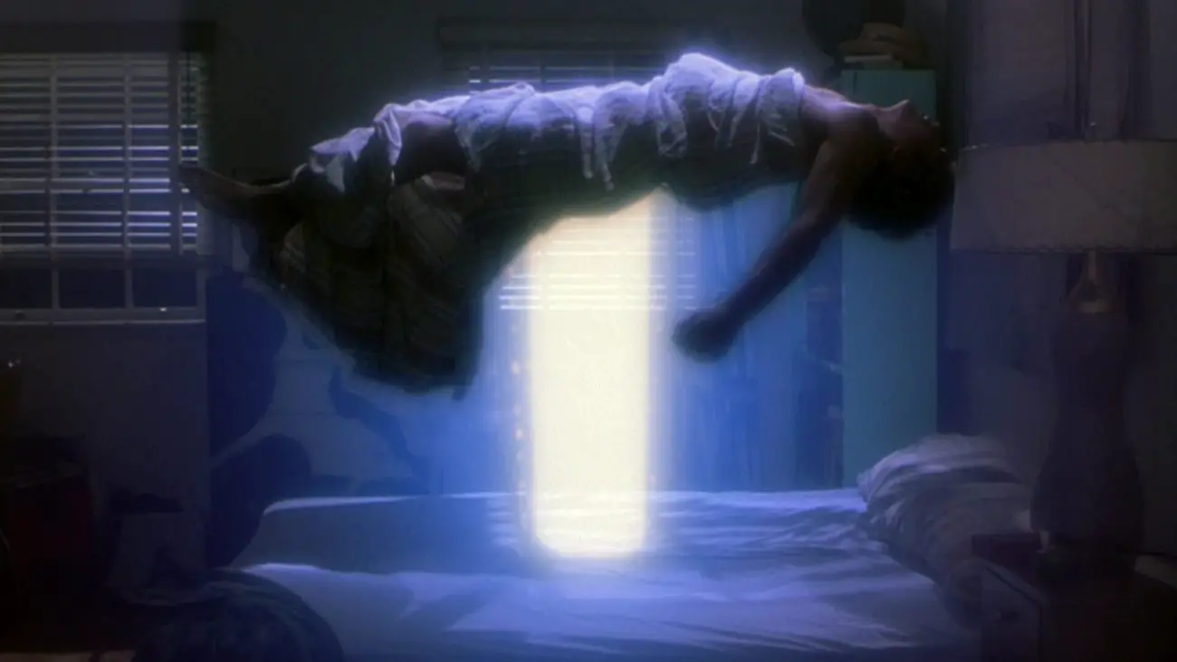 Alex levitating above his bed with a beam of light under him