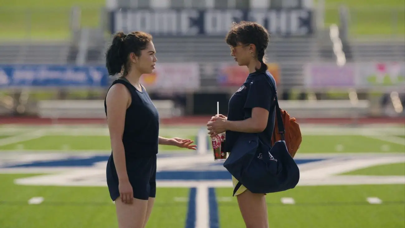 AJ and Paige look at each other on the football field