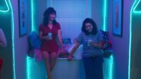 Paige and AJ laughing in neon room
