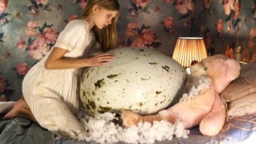 Young girl touches massive egg
