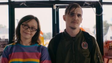 Patty (Emily Skeggs) and Simon (Kyle Gallner) stare at the camera in a fast-food restaurant.