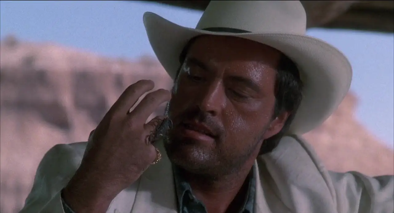 Cash, in a white suit and hat, lets a scorpion crawl on his hand.