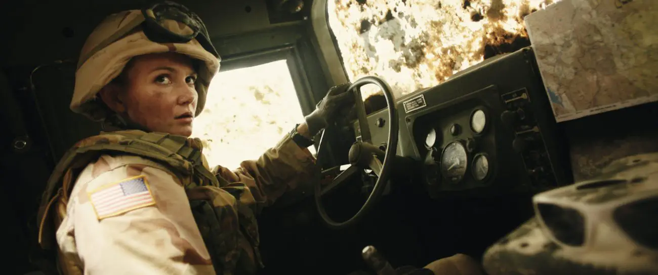 A woman soldier is at the wheel driving a truck.