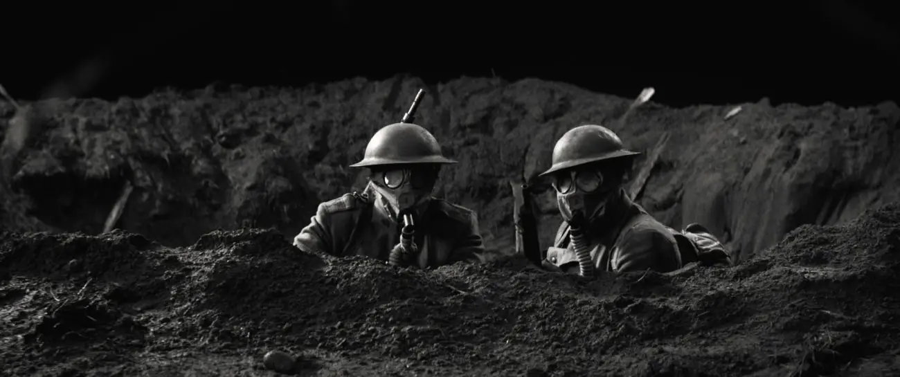 Two American World War I soldiers look over a foxhole wearing gas masks.
