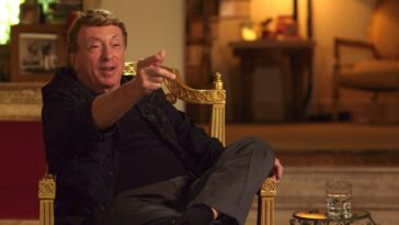 Larry Cohen sitting in a chair, pointing his finger