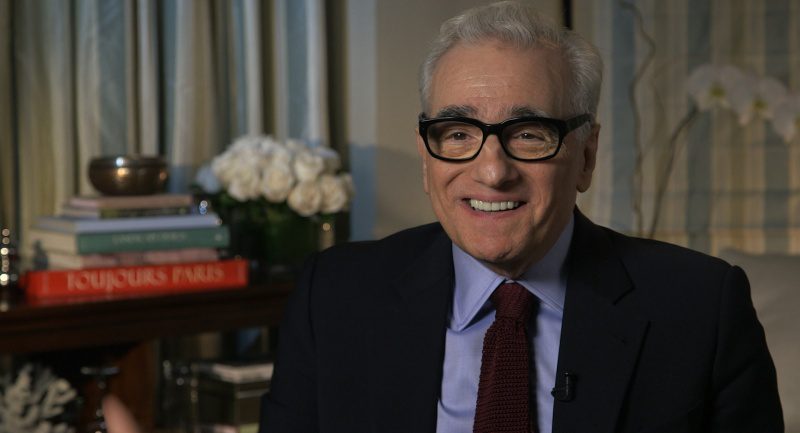Martin Scorsese sitting in a chair and smiling.